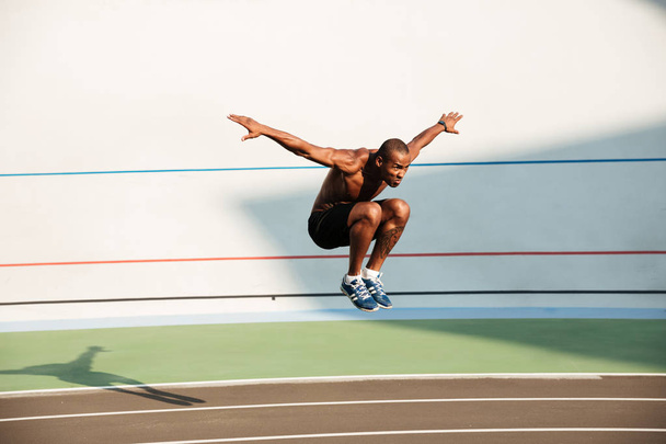 Portrait of a half naked strong fit african sportsman jumping - Foto, imagen