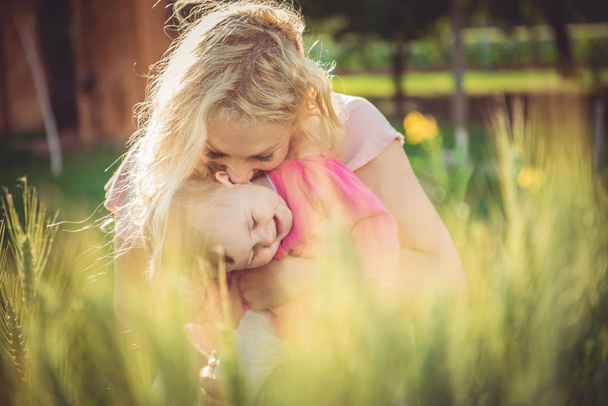 Mother holding and kissing baby girl - Fotografie, Obrázek