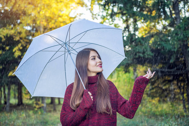 Mutlu genç kadın yağmur altında beyaz bir şemsiye ile Sunny Park'ta yürüyordunuz. Mevsim ve sonbahar ruh kavramı - Fotoğraf, Görsel