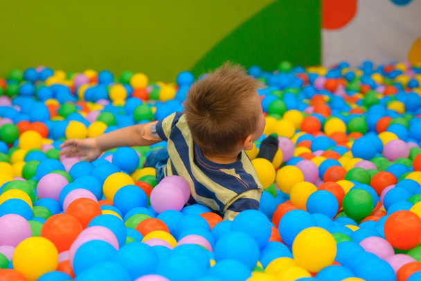 Мальчик в игровой комнате со многими маленькими цветными шариками
 - Фото, изображение