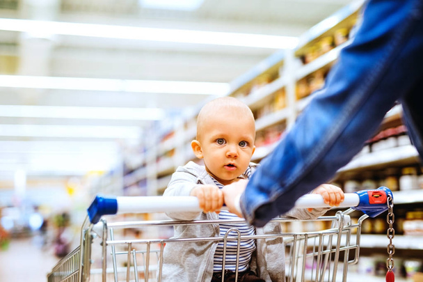 Young mother with her little baby boy at the supermarket. - 写真・画像