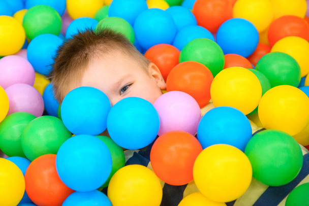 A boy in the playing room with many little colored balls - Photo, Image