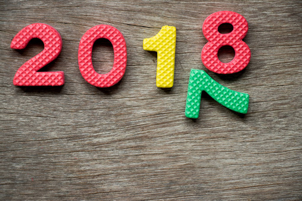 Alfabet pianki zabawki w sformułowanie 2018 i spadające numer 7 na tle drewna (koncepcja dla szczęśliwego nowego roku) - Zdjęcie, obraz