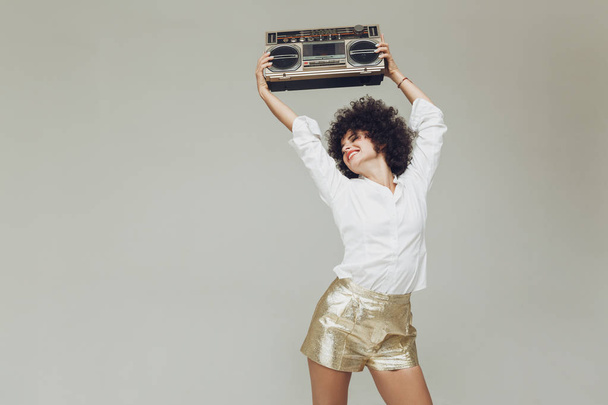 Emotional retro woman dressed in shirt holding boombox. - Foto, Bild