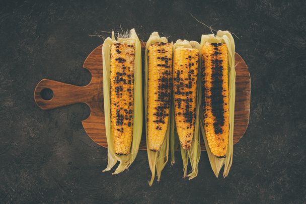 grilled corncobs on cutting board - Фото, изображение