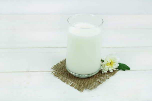 A bottle of milk and glass of milk on a wooden table on a  background - Foto, Imagen