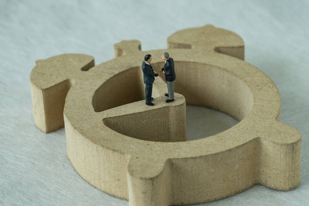 Miniature figure businessmen handshaking and standing on wooden  - Фото, изображение