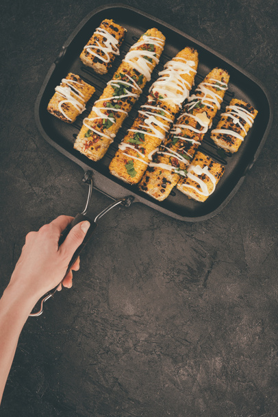 woman holding grill pan with corn - Foto, afbeelding