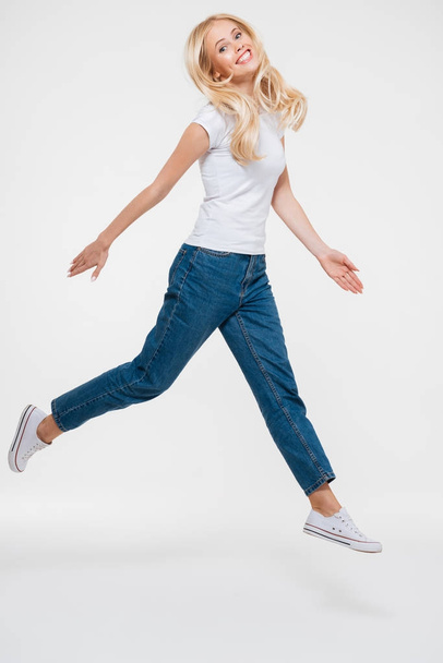 Full length portrait of a pretty joyful woman jumping - Foto, imagen