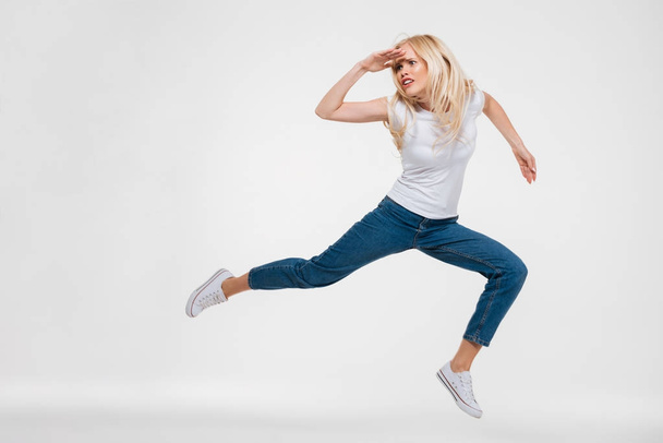 Full length portrait of a pretty woman jumping and looking - Φωτογραφία, εικόνα