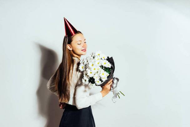 smiling happy girl celebrating something, in a red cap and with a bouquet of white flowers - Foto, Imagen