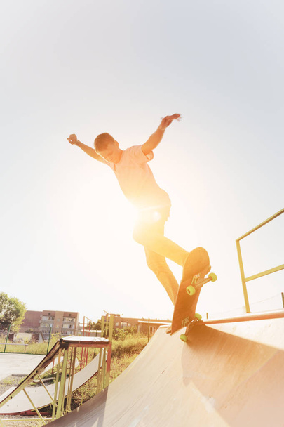 Teen skater hang up over a ramp on a skateboard in a skate park - Photo, image