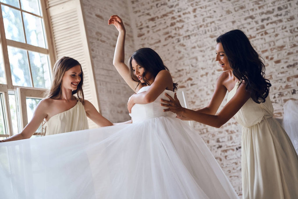 bridesmaids helping bride to get dressed - Photo, image