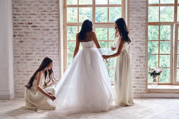 bridesmaids helping bride to get dressed - Zdjęcie, obraz