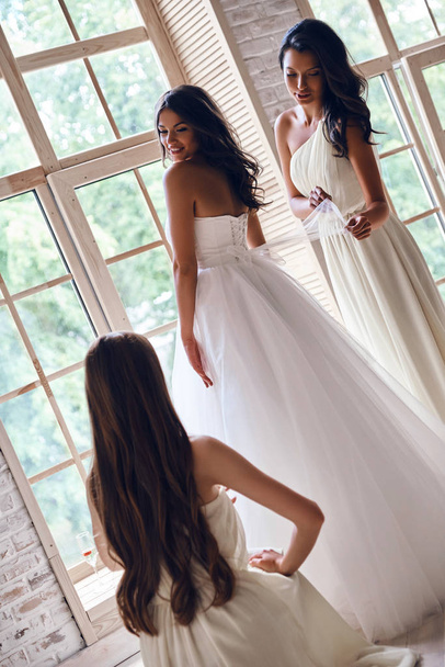 Damas de honor ayudando a la novia a vestirse
 - Foto, Imagen