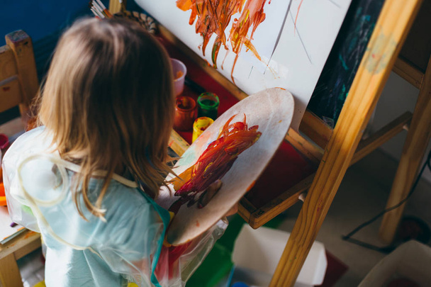 little girl drawing with paints and palette - Fotó, kép