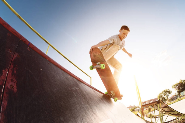 Teen skater hang up over a ramp on a skateboard in a skate park - 写真・画像