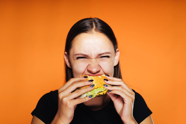 hungry girl wants to lose weight, but eagerly eats a harmful burger - Fotoğraf, Görsel