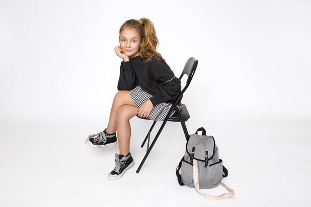 niedliches kleines Mädchen in Schulkleidung und Schulrucksack auf weißem Hintergrund - Foto, Bild