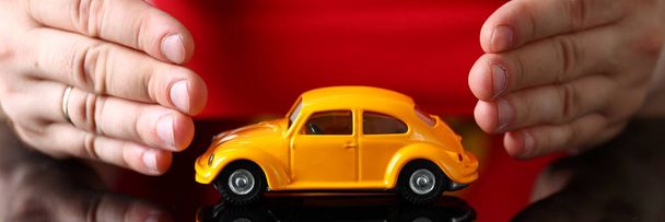 Male arm in cover yellow toy car - Foto, imagen