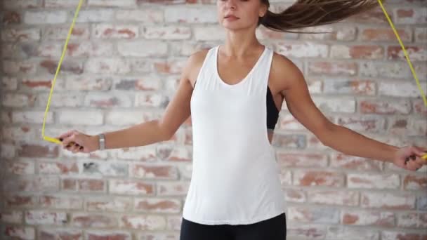 Jonge vrouw met een slank figuur is energiek springen met touw in sportschool. - Video