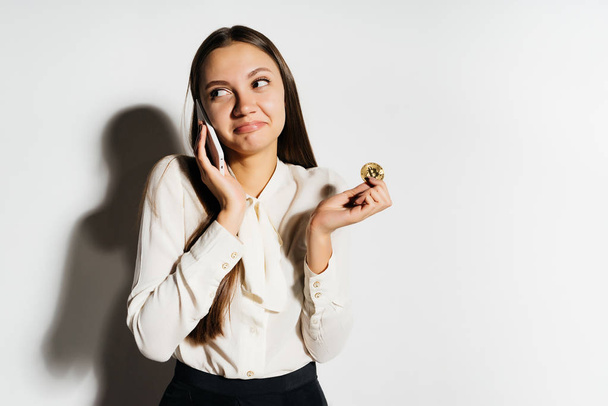 young business woman talking on the phone, holding a golden bitcoin - Fotografie, Obrázek