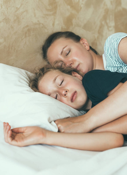 Moeder en dochter liggen te slapen in omhelzing. - Foto, afbeelding