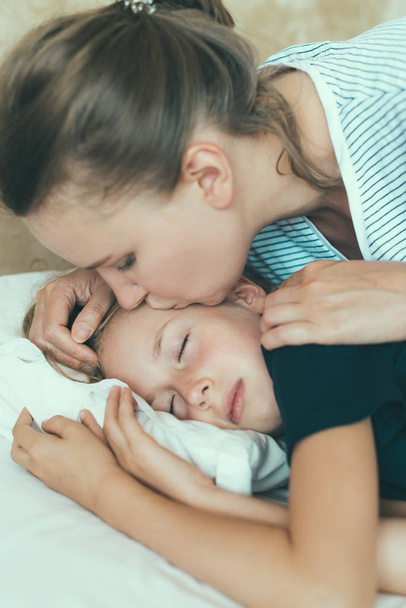 Мама цілує її дочка перед сном. - Фото, зображення