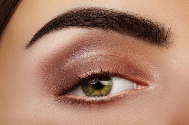 Close-up Beauty of Woman's eye. Sexy smoky Eyes Makeup with brown Eyeshadows. Perfect strong Shape of Eyebrows - 写真・画像