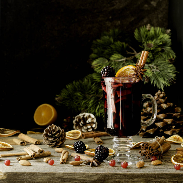 copa de vino caliente caliente con especias para el nuevo año con ingredientes para cocinar, nueces y decoraciones navideñas
 - Foto, imagen