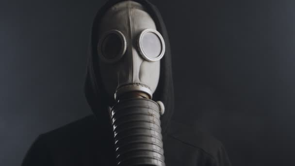 man in een gas masker in rook in een donkere kamer - Video