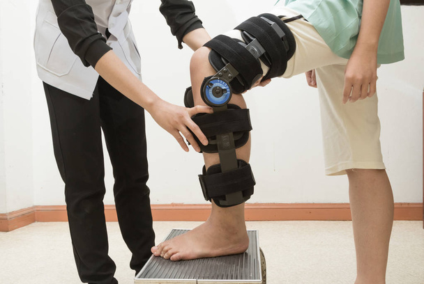 セラピストが患者の脚に膝装具の継手 - 写真・画像
