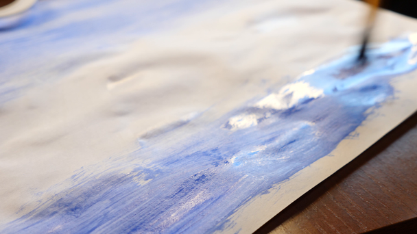 de kunstenaar schildert verf op een wit vel. Close-up van een kwast. 4k, slow-motion-video schieten - Video