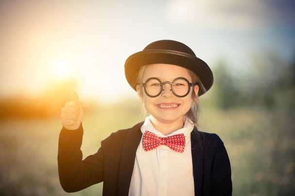 Funny little girl in bow tie and bowler hat showing thumb up. - Foto, afbeelding
