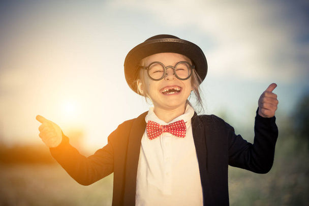 Funny little girl in bow tie and bowler hat showing thumbs up. - 写真・画像
