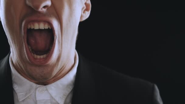 aggressive businessman in a suit is screaming and showing anger on a black background. Angry boss. The danger of violence - Footage, Video