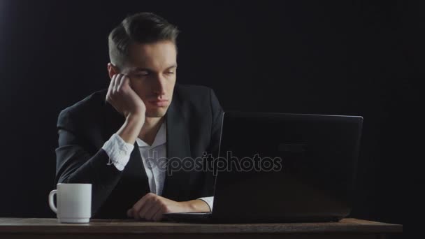 Aburrido hombre de negocios sentado junto al escritorio en la oficina oscura
 - Metraje, vídeo
