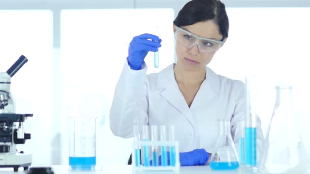 Wetenschappelijk onderzoeker, arts kijken naar blauw oplossing in reageerbuis in Laborator - Video