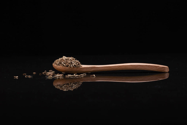 Cumin seed  over Black background with wooden spoon - Photo, Image