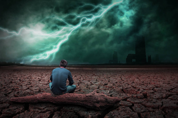 Αφηρημένος άνδρας κάθεται στο ξύλο στη γη το ξηρό έδαφος ραγισμένα. Με καταιγίδα - Φωτογραφία, εικόνα