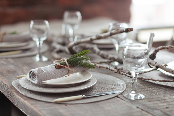 Rustic Christmas served wooden table with vintage silverware, candles and fir twigs. New Year Celebration, Christmas dinner served in loft interior - Foto, imagen