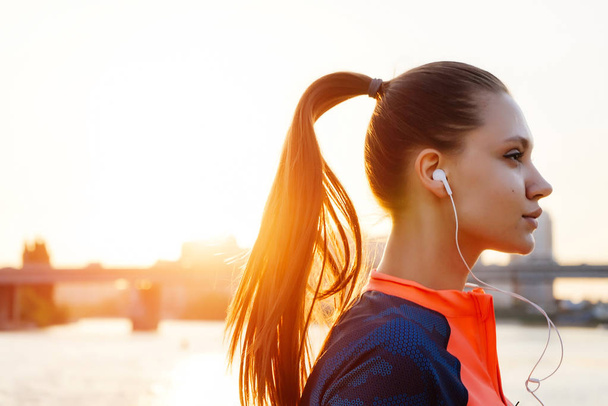 girl in sports uniform performs an evening run on the sunset background - Zdjęcie, obraz