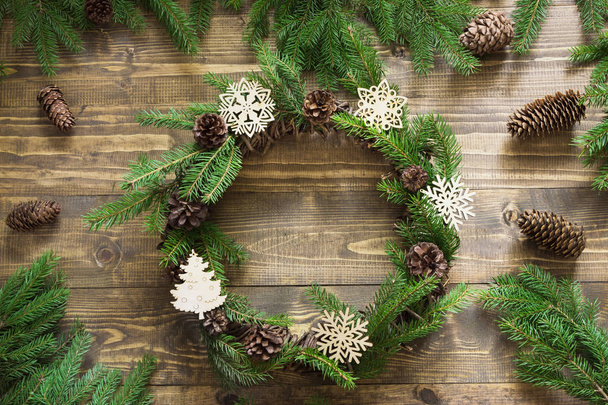 Christmas wreath with fir branches and decorative snowflakes on wooden tabletop. Flat lay. - Фото, зображення