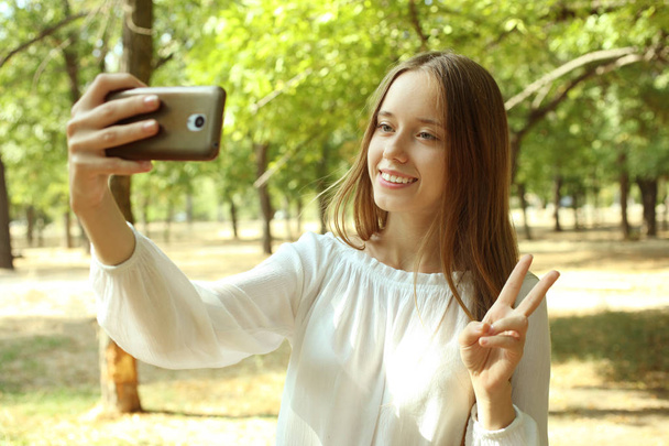 meisje is het maken van een selfie in een park  - Foto, afbeelding