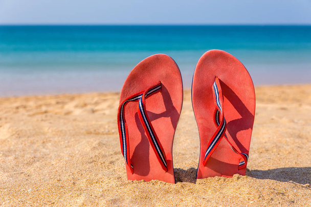 Две красные тапочки на пляжном песке
 - Фото, изображение