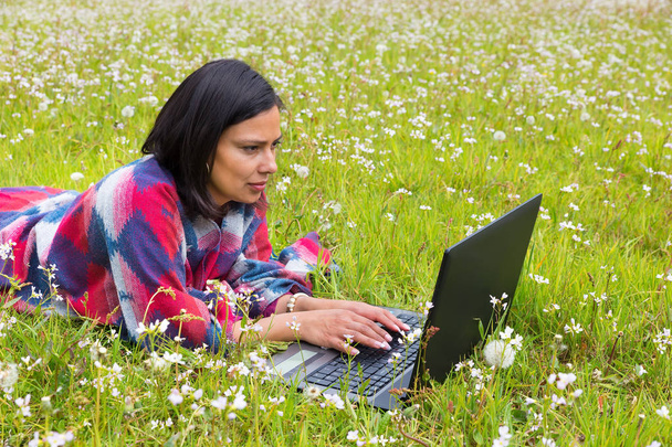 Žena s počítačem ležící v louce s květinami - Fotografie, Obrázek