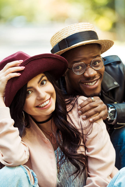 smiling multicultural couple in hats - Zdjęcie, obraz
