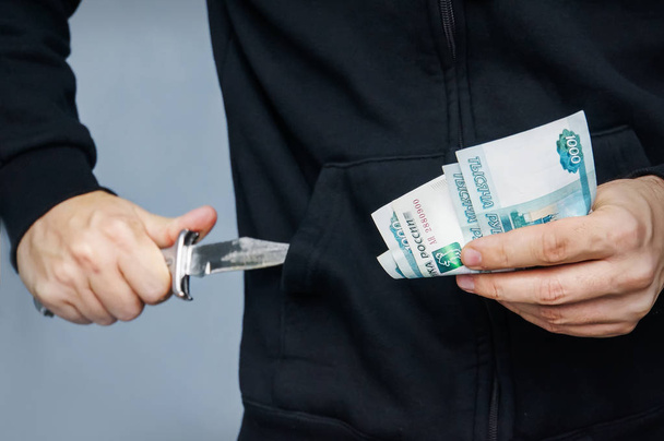 Розбійник з ножем у руці і російські гроші - Фото, зображення