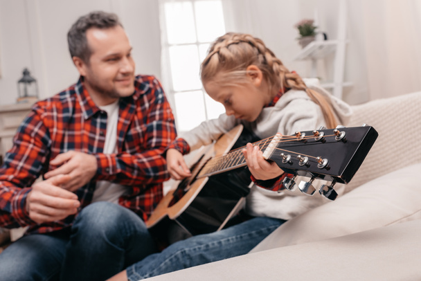 isä ja tytär soittamassa kitaraa
 - Valokuva, kuva