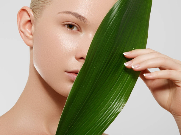 Skincare, Wellness, Spa. Clean soft Skin, healthy Fresh look. The concept of a healthy skin. Portrait of a beautiful girl against a background of tropical leaves. Spa concept. Natural beauty - Photo, Image